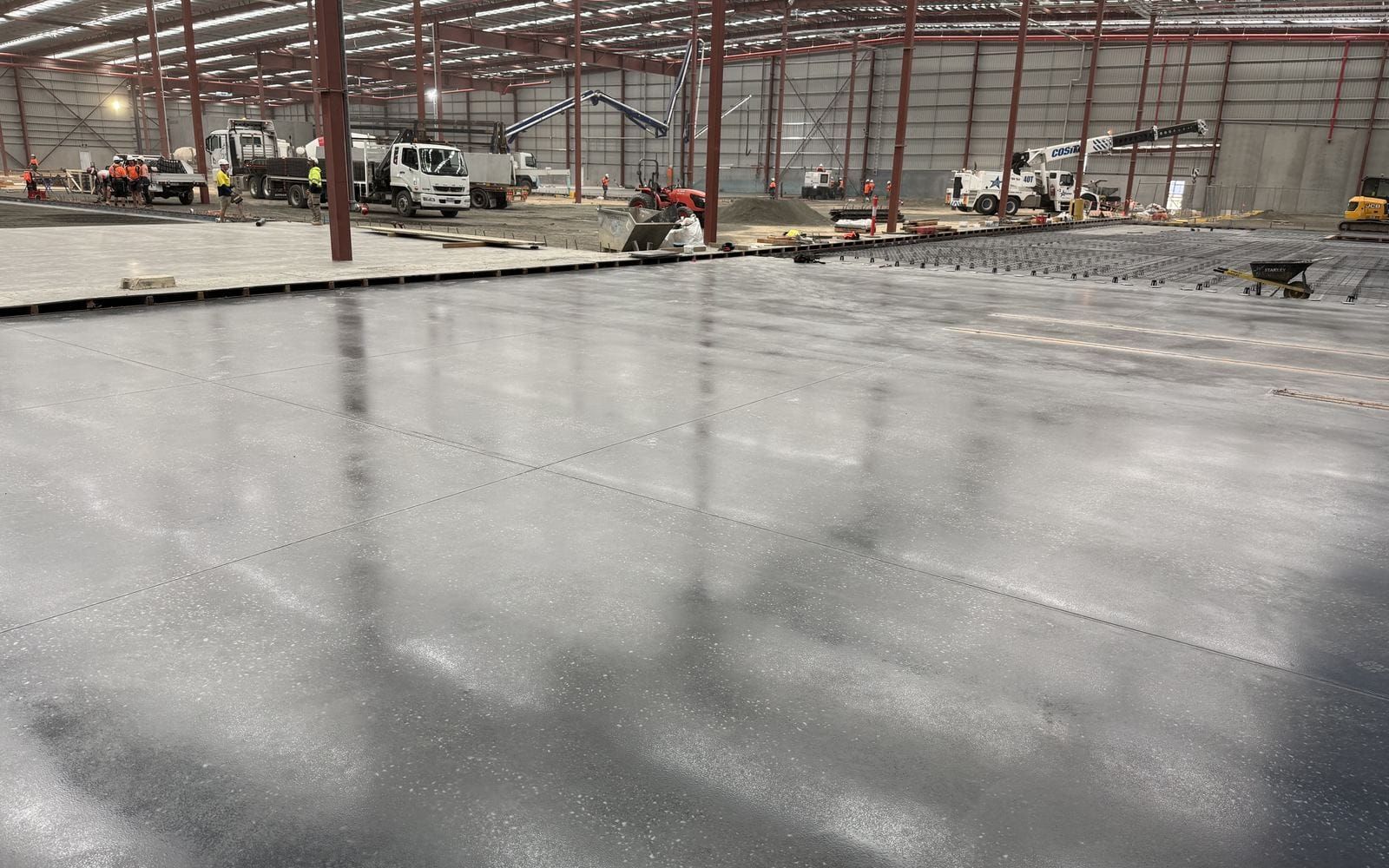 A burnished concrete warehouse floor reflecting the roof lights