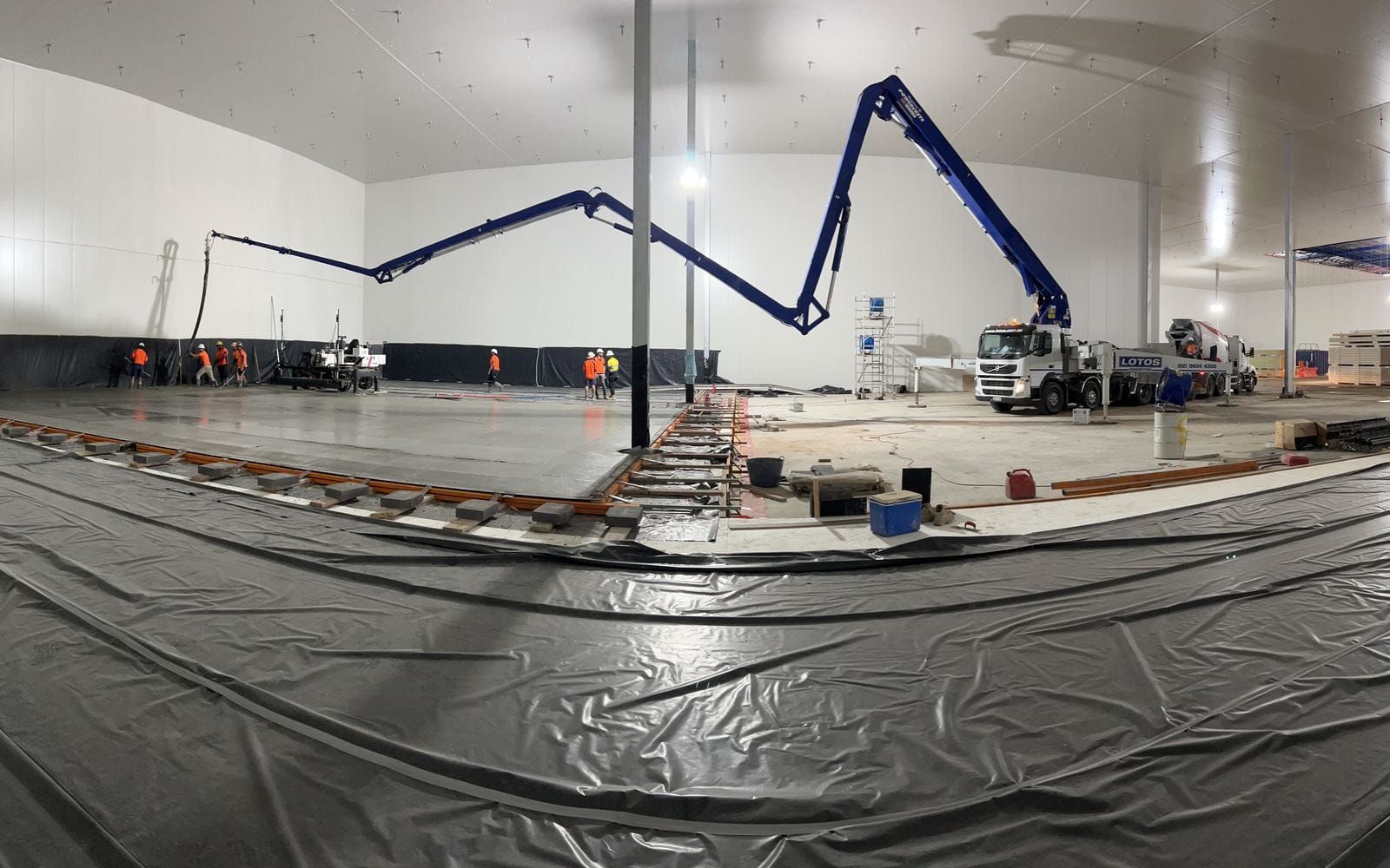 Wide view of a wearing slab pour underway inside the cold store