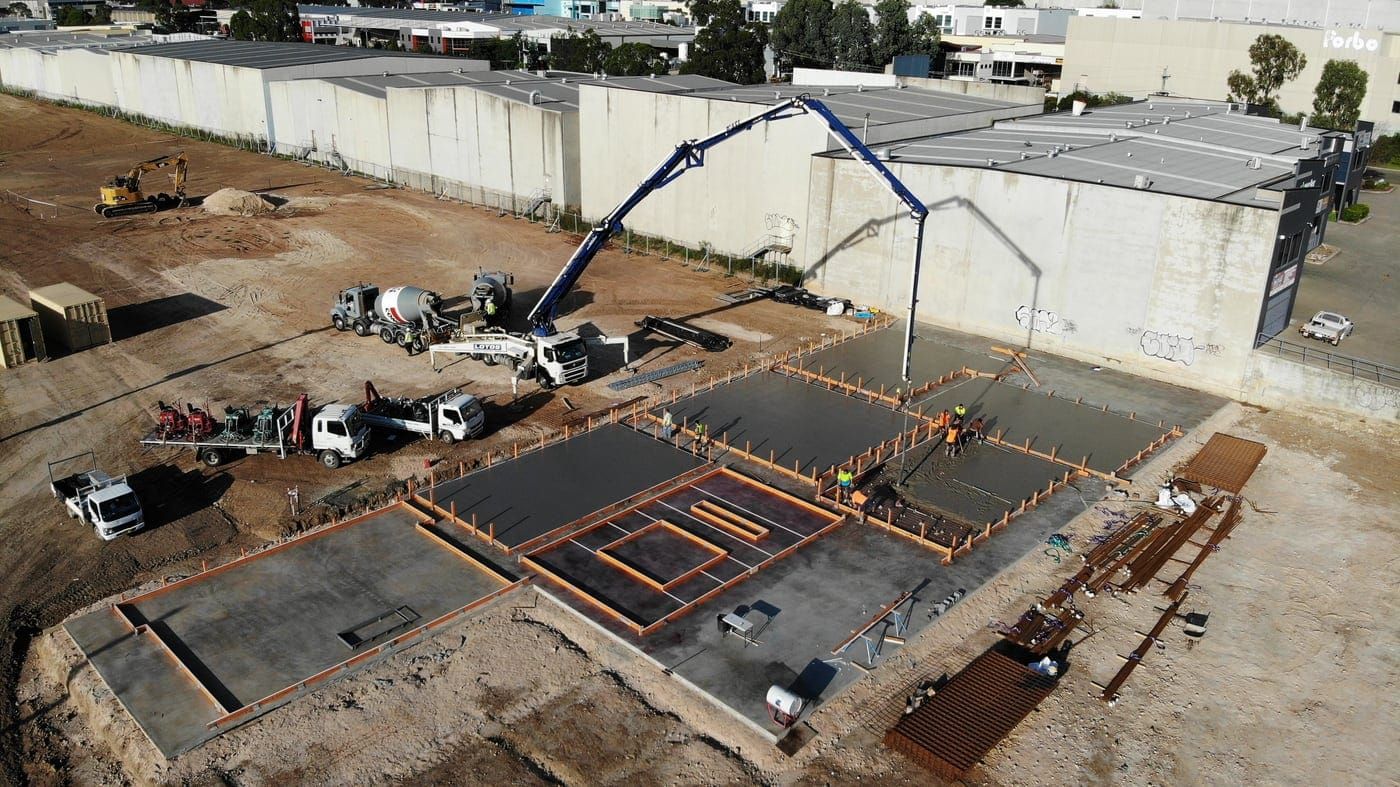 A Lotos boom pump placing concrete into formed slab bays on a commercial site